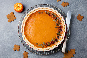 Wall Mural - Tasty pumpkin pie, tart made for Thanksgiving day in a baking dish. Grey stone background. Top view