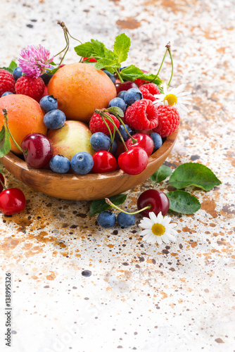 Fototapeta na wymiar bowl with seasonal fruit and berries, vertical closeup