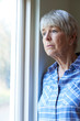 Senior Woman Suffering From Depression Looking Out Of Window
