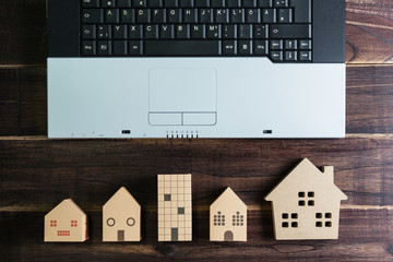 Top view of office stuff with laptop and Wooden house toy on wooden table.Concept workplace.Real estate concept, New house concept, Finance loan business concept.
