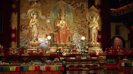 Wall Mural - Buddha images stand over a colorful altar inside a temple in Singapore