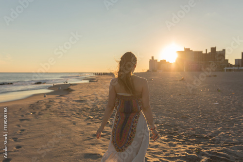 mloda-kobieta-idzie-na-coney-island-beach-o-zachodzie-slonca-nowy-jork-usa