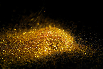 Wall Mural - Sprinkle glitter gold dust on a black background with copy space