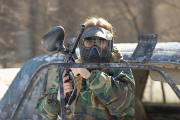 Wall Mural - girl playing paintball in overalls with a gun.