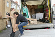 © Mint Images - Removals business. Two men lifting an awkward package onto a van.