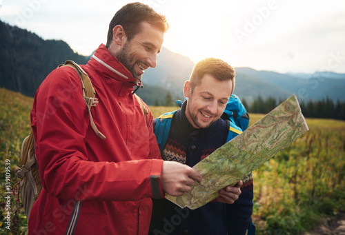 Fotografia Smiling hikers reading a trail map in the wilderness