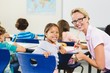 © WavebreakMediaMicro - Smiling teacher helping kids with their homework in classroom