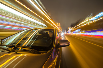 Canvas Print - Blurred urban look from fast driving car to back side and driver at winter night. Longexposure shot.