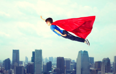 Wall Mural - boy in red superhero cape and mask flying on air