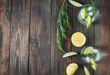 Wall Mural - Alcoholic drink gin tonic cocktail with lemon, rosemary and ice on rustic wooden table, copy space