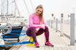 © ratmaner - Slim girl in sports wear resting after exercise in seaport, healthy active lifestyle