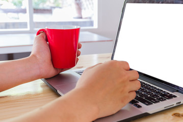 Man's hands using laptop with blank screen on desk in home