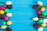 colorful easter eggs and bouquet of tulips on wooden background with space for a text