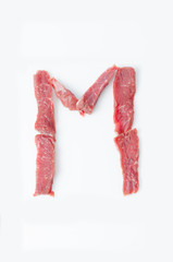 The letter M Latin alphabet of red beef meat on a white background