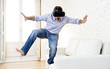 © Wordley Calvo Stock - man standing on sofa couch excited using 3d goggles watching 360