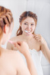 © geargodz - woman in bath towel brushing teeth with mirror in bathroom