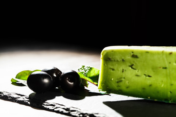 Wall Mural - Black olives and green leaves on black dish