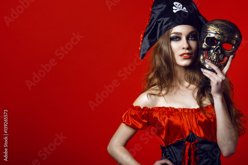 Fényképezés Portrait of gorgeous sexy woman with provocative make-up in pirate costume holding skull mask next to her face