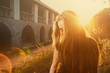 Young woman hide her face with long blond hair backlit by sun selective focus toned image, sun flares