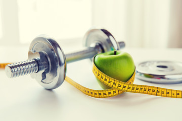 close up of dumbbell and apple with measuring tape