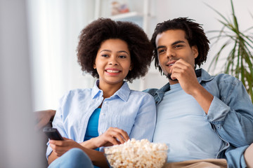 Wall Mural - smiling couple with popcorn watching tv at home