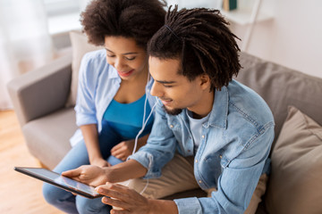 Poster - happy couple with tablet pc and earphones at home