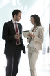 © PhotoAlto - Smiling business people discussing with each other in office corridor