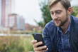 © PhotoAlto - Man relaxing in park, looking at multimedia smartphone