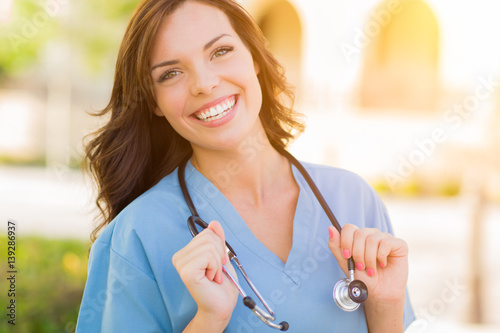 Fotografie, Obraz Portrait of Young Adult Female Doctor or Nurse Wearing Scrubs and Stethoscope Outside