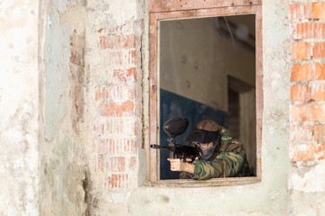 Wall Mural - girl playing paintball in overalls with a gun.