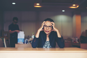 Frustrated business woman sitting at the table in office.