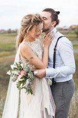 Wedding. Wedding by the sea. Young couple in love, bearded groom and bride in wedding dress at the seaside. Couple in love walking around the sea and the rocks near the place of the wedding ceremony.