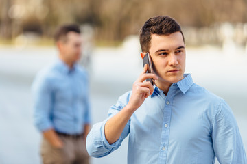 Businessman talking at his phone with friend on blur background