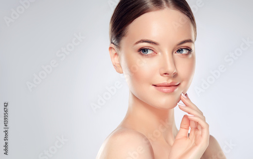 Zdjęcie XXL Piękna młoda kobieta z Czystą świeżą skórą dotykać własnej twarzy. Zabieg na twarz . Kosmetologia, piękno i spa