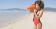 © Dash - Lifeguard female wearing red swimsuit blowing a whistle holding rescue float. Tarifa beach. Provincia Cadiz. Spain.