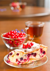 Piece of berry pie on saucer and red currants