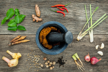 Wall Mural - Assortment of Thai food Cooking ingredients and spice red curry paste ingredient of thai popular food on rustic wooden background. Spices ingredients chilli ,pepper, garlic and Kaffir lime leaves .