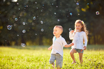 Wall Mural - Young boy and girl looking at soap bubbles