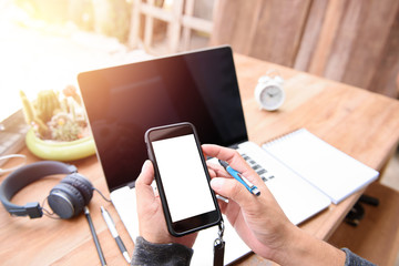 Poster - Businessman holding a smart phone with white screen.on a desk outdoors. One corner of the house With the morning light