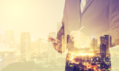 Poster - Double exposure of Business man working with a digital tablet with cityscape blurred building background,investment, success and profitable business concepts