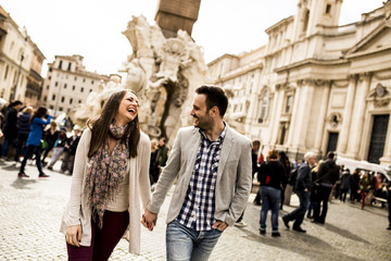 Wall Mural - Casual young couple holding hands walking in Rome, Italy, Europe