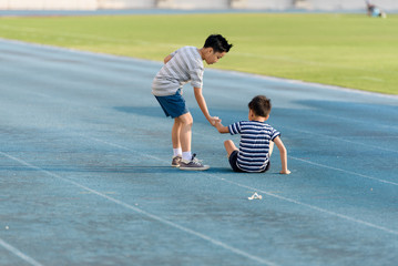 boy help each other on blue track after fall