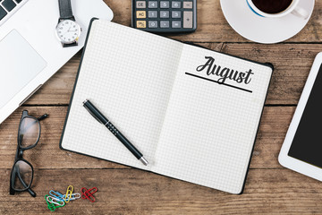 Poster - August (German and English) month name on paper note pad at office desk