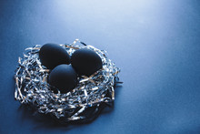 Three Black Eggs In A Nest Made Of Silver Strings, On  A Dark Blue Background, Easter Concept 