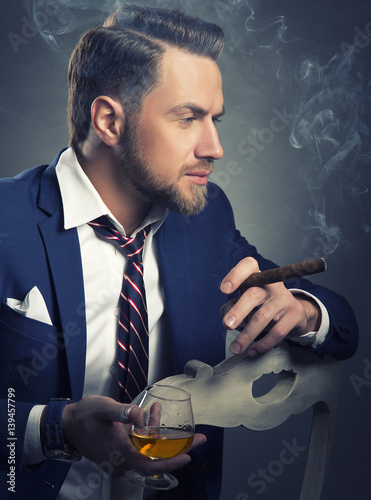 Fotografija Man relaxing with cognac and cigar after hard work in office