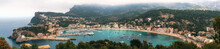 Panoramic View Of Port De Soller With Harbour, Yachts, Tourist Boats, Colorful Architecture And Beach On A Cloudy Day. Landmark Of Mallorca, Spain