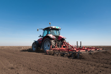 Wall Mural - Farmer in tractor preparing land with seedbed cultivator in early spring