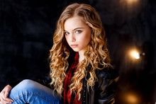 A Beautiful Blond Girl With Curly Hair In Black Leather Jacket And Jeans