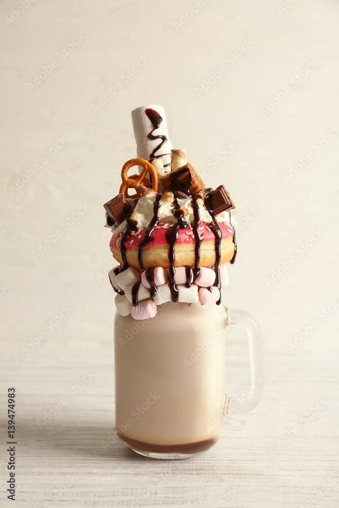Milkshake, donut and other sweets in jar on white wooden background