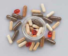 Wall Mural - Different medicinal capsule spill out of a glass jar on a light